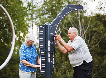 two elderly people exercising on an outdoor gym
